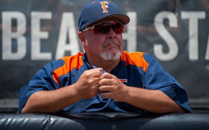 man wearing a baseball uniform, sunglasses and a baseball cap