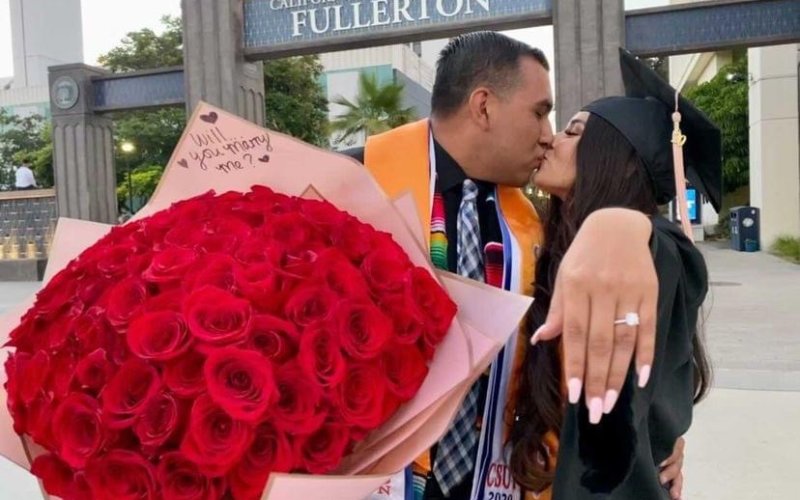 man and woman holding red roses showing off a ring