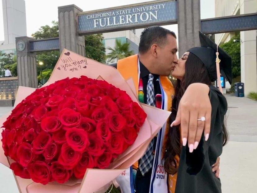 man and woman holding red roses showing off a ring