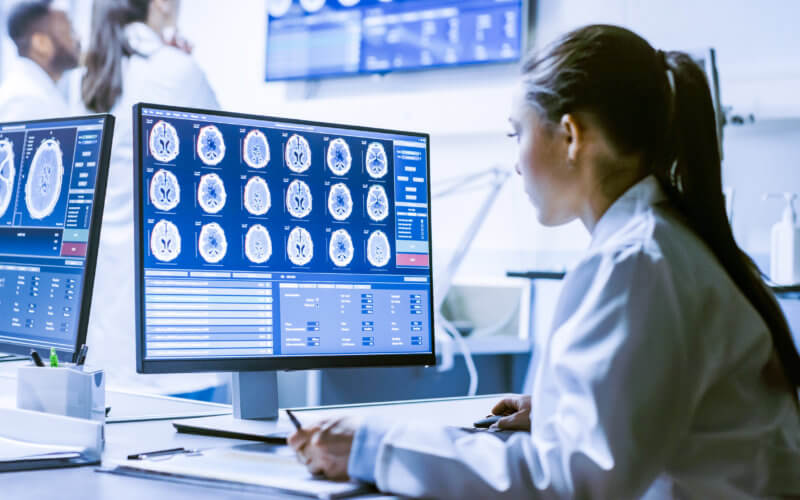 Female Medical Research Scientist Working with Brain Scans on Her Personal Computer, Writing Down Data in a Clipboard. Modern Laboratory Working on Neurophysiology, Science, Neuropharmacology.