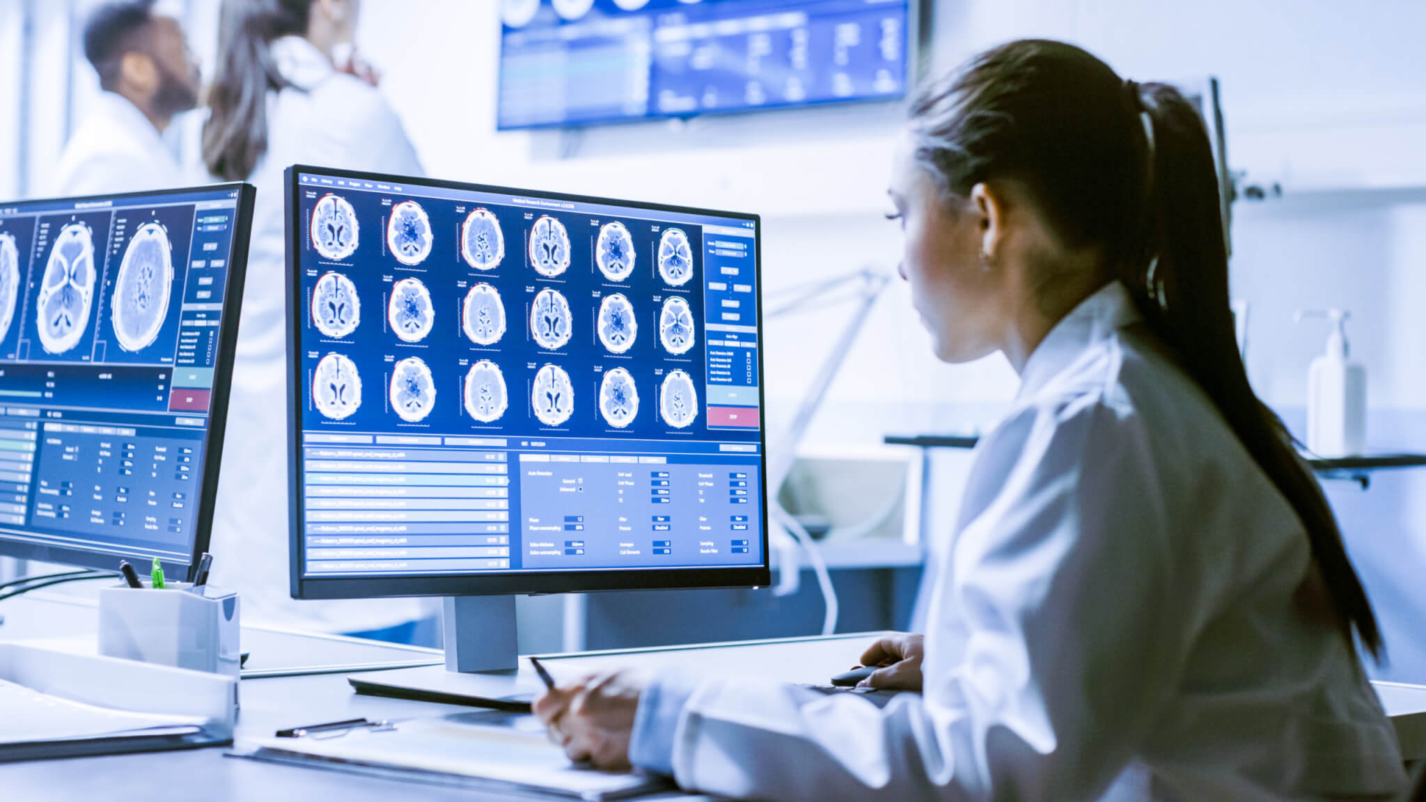 Female Medical Research Scientist Working with Brain Scans on Her Personal Computer, Writing Down Data in a Clipboard. Modern Laboratory Working on Neurophysiology, Science, Neuropharmacology.