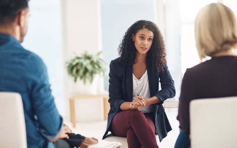 Latinx therapist speaking to a couple during a counseling session