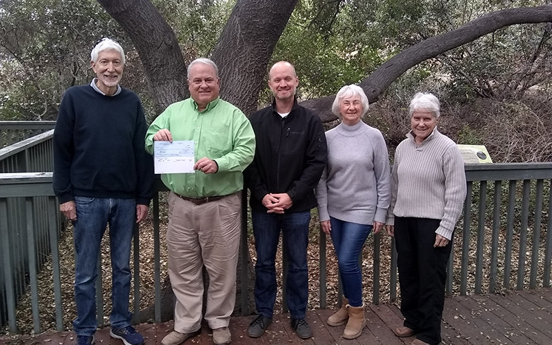 Check presentation, one male and two females presenting donation to directors