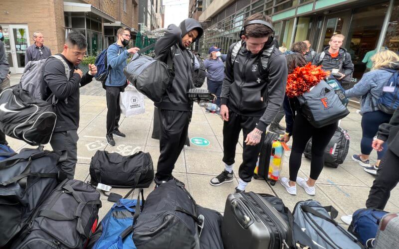 men in gray sweats picking up luggage