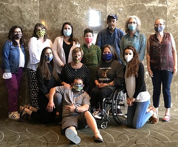 A group of individuals with and without disabilities, with masks on, facing the camera. Some are standing, some are kneeling, and some are sitting. This is the Cal-TASH Board.