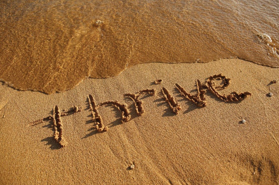 "Thrive" written in the sand