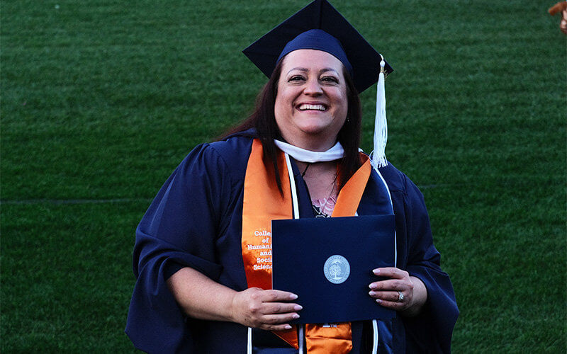 Vivian Valenti-Flores holds up diploma while posing for photo