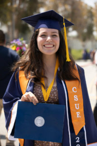 Angelina Guzman poses in Commencement regalia while holding diploma cover