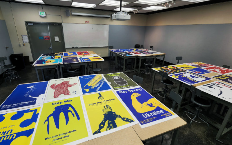 Printed posters laid across tables in a classroom.
