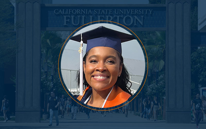 Graduation headshot of African American female with navy blue cap and white tassel with the Cal State Fullerton archway background