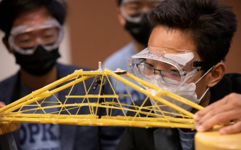 Student works with spaghetti bridge