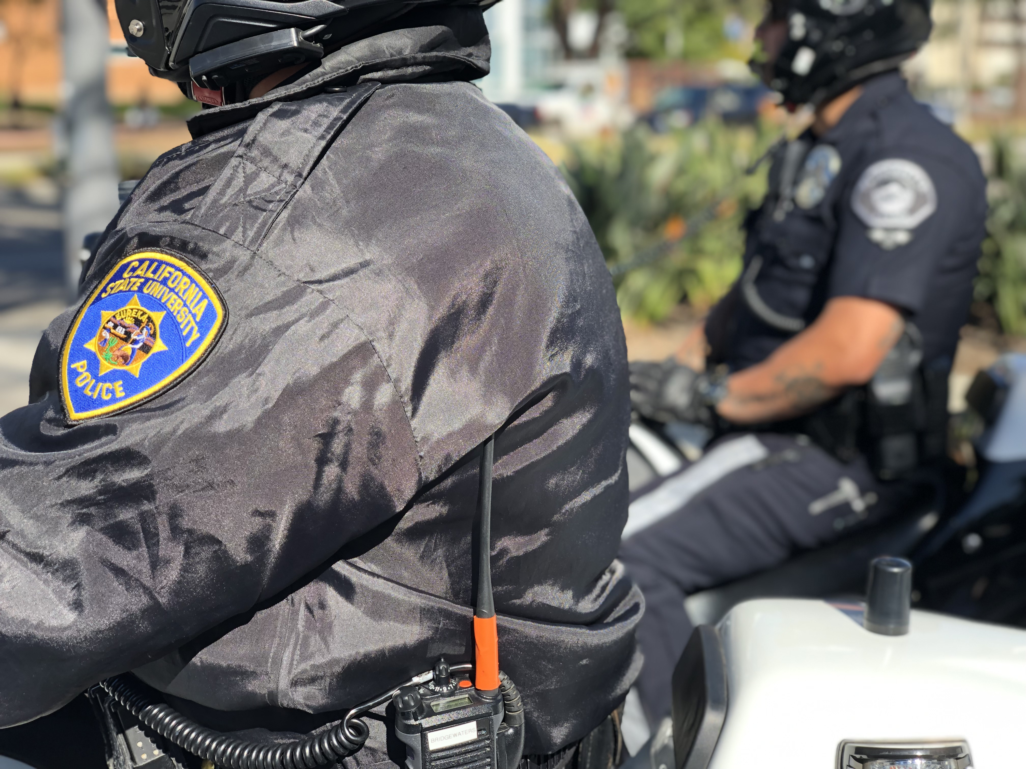 Two motor officers in uniform sitting on the street corner monitoring traffic