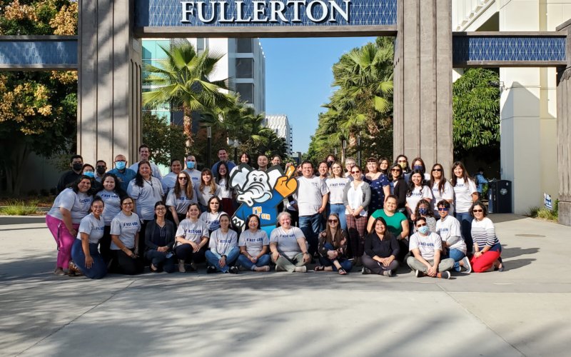 Group of first-generation faculty and staff gathered at the promenade entrance celebrating First Gen Week