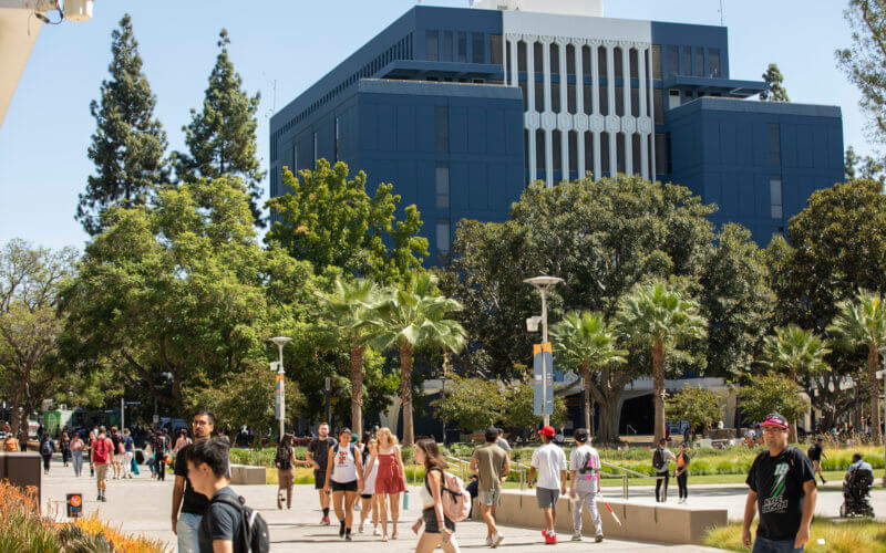 Students walk on campus in front of the Humanities and Library buildings