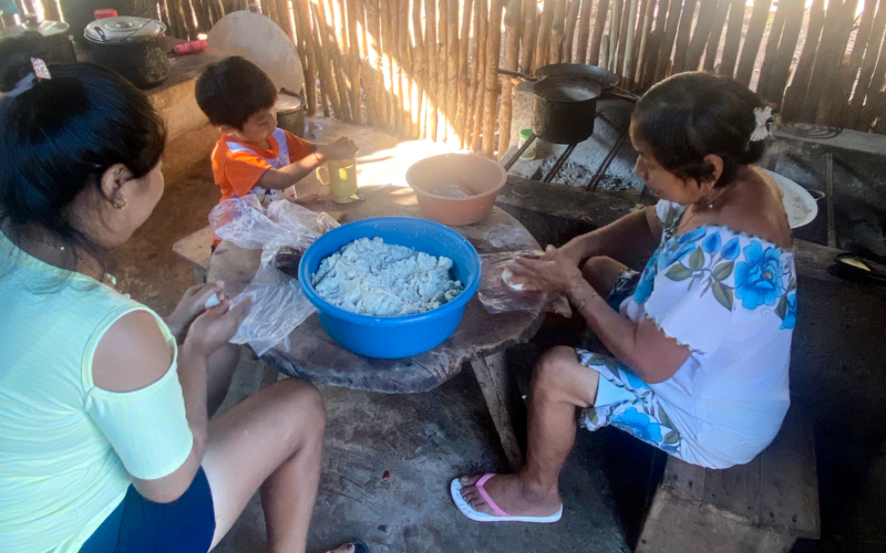 Mother and grandmother teach young boy how to cook.