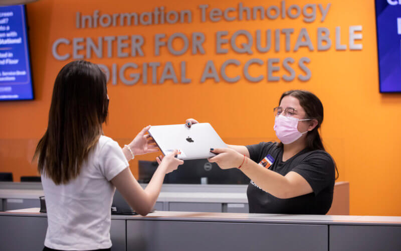 Employee handing student a laptop