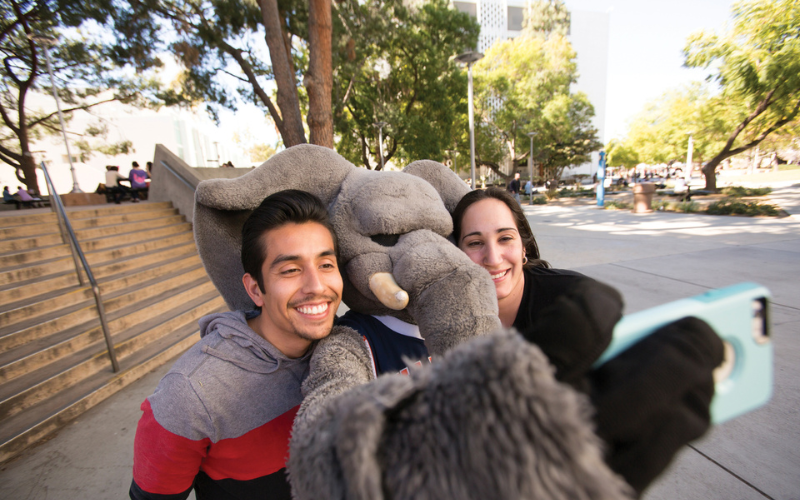 Tuffy taking a photo with two students