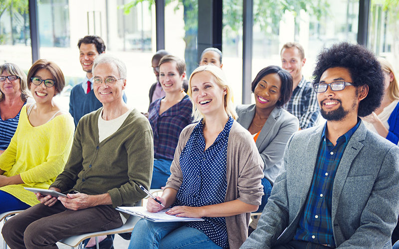 Diverse group of adults, dressed in casual or business casual attire, paying attention to a speaker