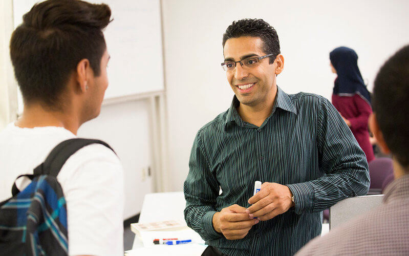 Professor Hassan Yousefi speaks with a student about adding his class.