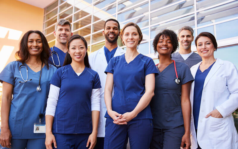 Smiling medical team standing together outside a hospital