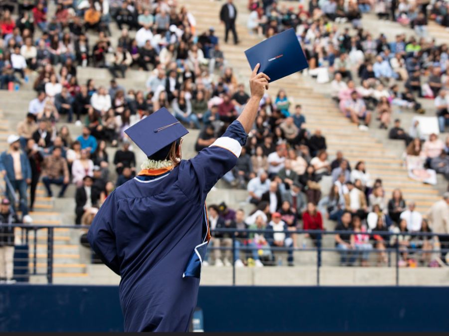Graduate holding their diploma up