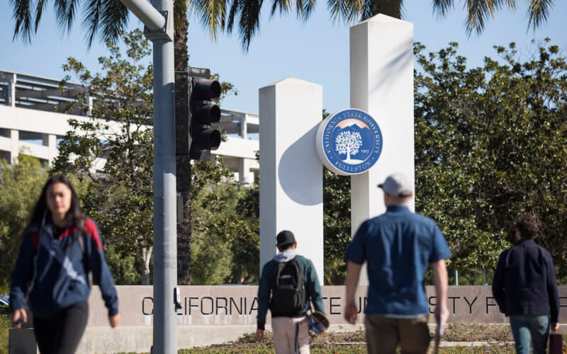 Students walk in front of CSUF mounument.