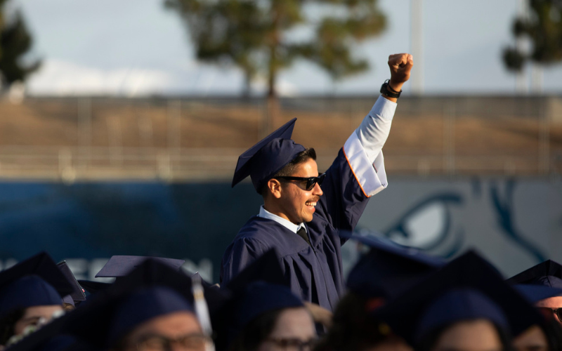 Student in regalia with a fist in the air