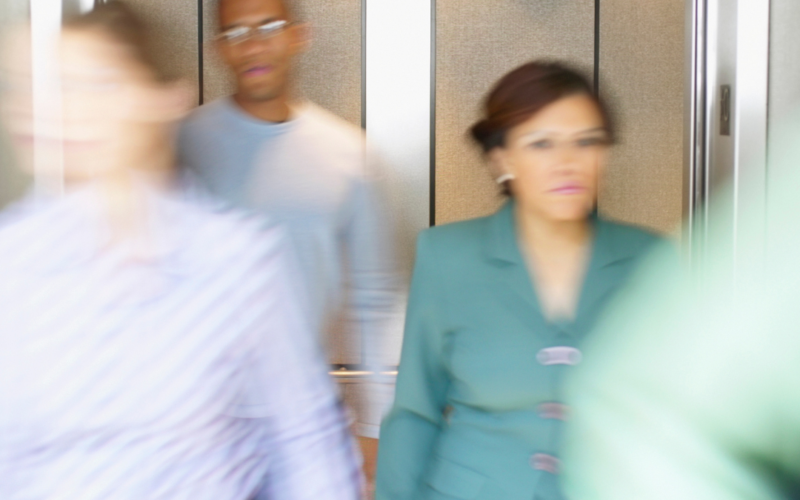 Individuals dressed in professional work attire quickly exiting a building elevator