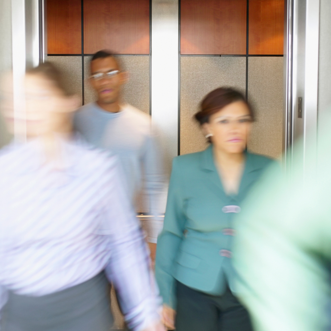 Individuals dressed in professional work attire quickly exiting a building elevator