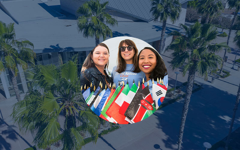 Circular image frame of three female students posing with several mini international flags. Behind the circular frame is a background image of the CSUF Clayes Performing Arts Center, lined by very tall palm trees.