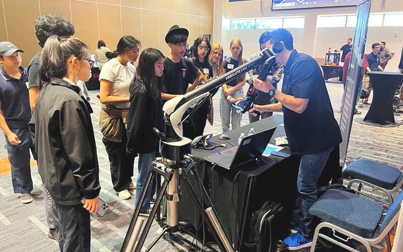 Engineer from Hexagon demonstrating to a group of diverse high school students how to use a 3D Scanner.