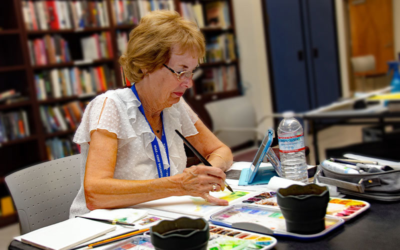 Female older adult participating in an OLLI watercolor painting activity.