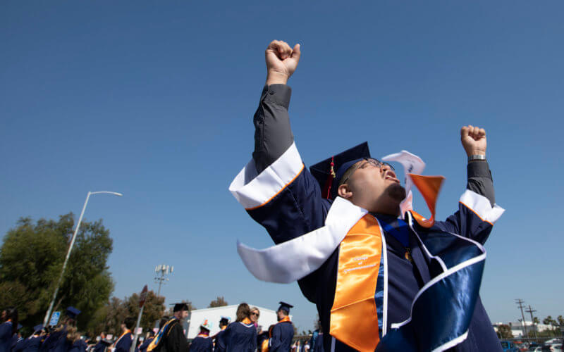 Graduate raises hands in air