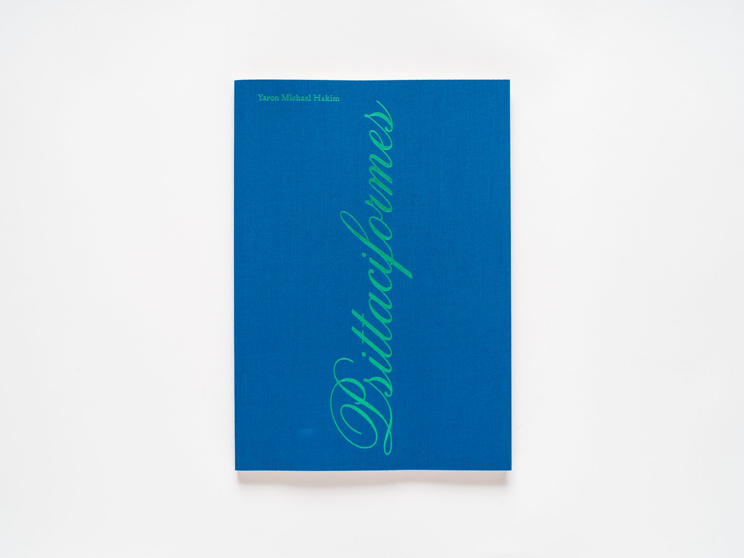 blue book cover with green foil text that reads Yaron Michael Hakim at the top left corner and the title Psittaciformes in cursive text that reads vertically from the bottom center of the cover to the top.