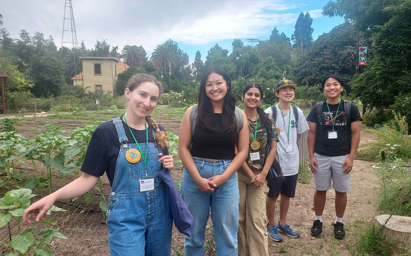 Five diverse student interns standing in front of a sprouting flower field at the Arboretum.