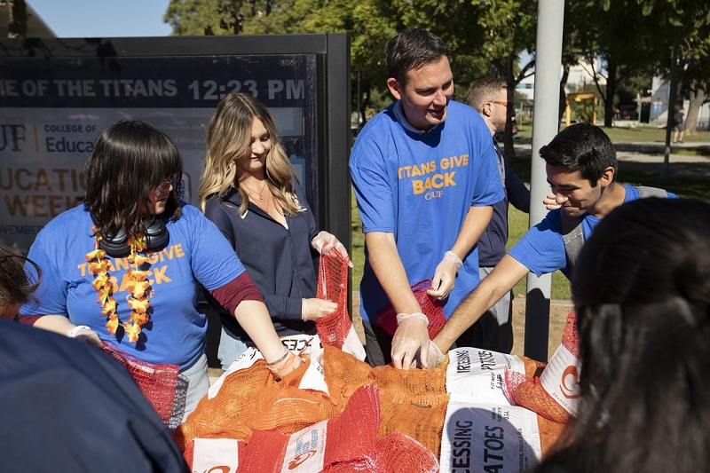 People wearing Titans Give Back t-shirts packing bags of potatoes