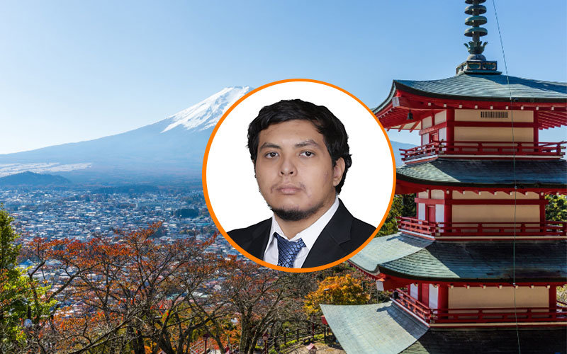 Headshot of Edward Hernandez in a circular, orange-outlined frame. The background is a view of Mt. Fuji in Japan.