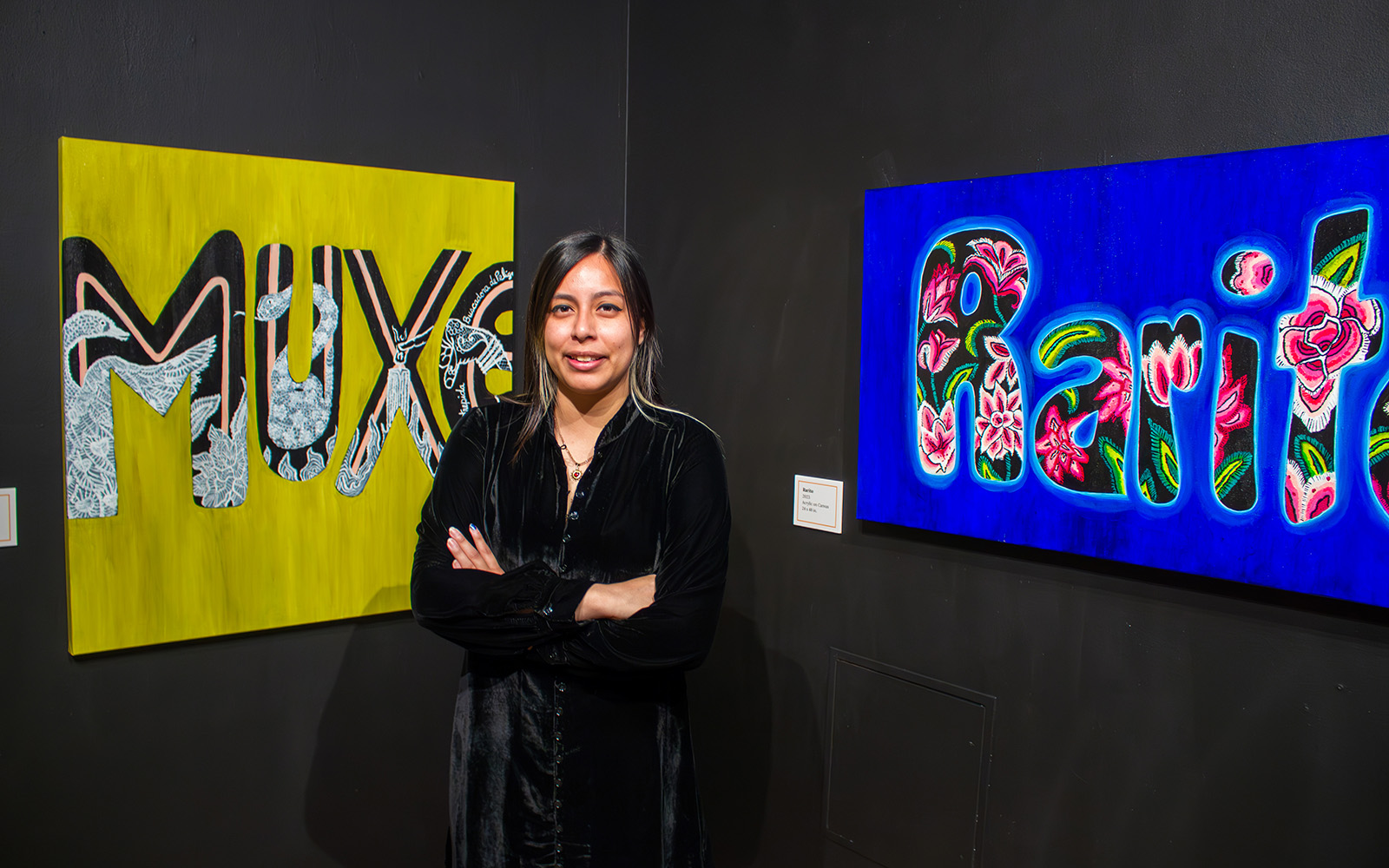 A woman standing in front of two paintings.