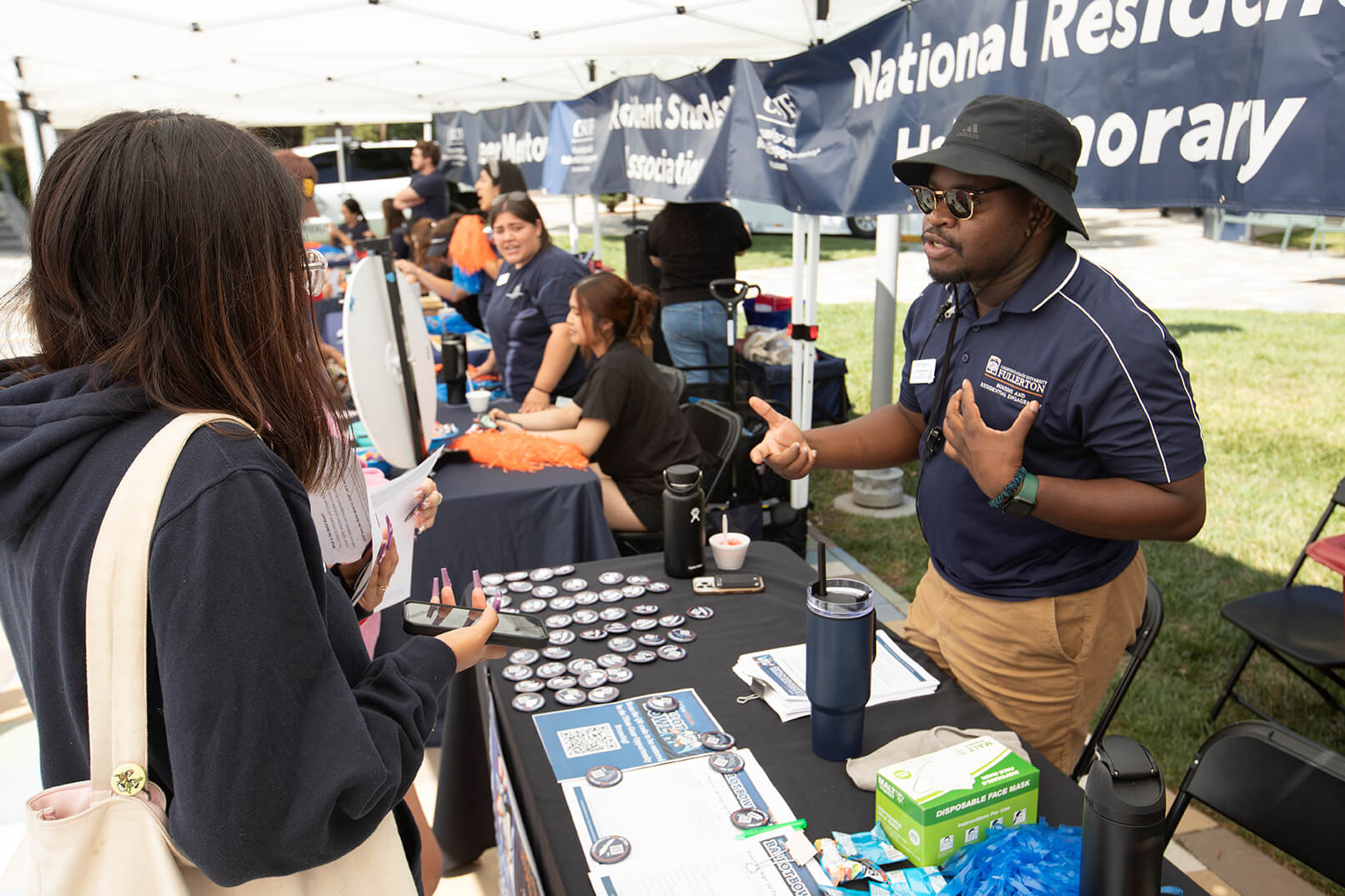 Shaquille Manley, senior community coordinator in Cal State Fullerton’s Housing and Residential Engagement department, speaks with a student about the voter registration process.
