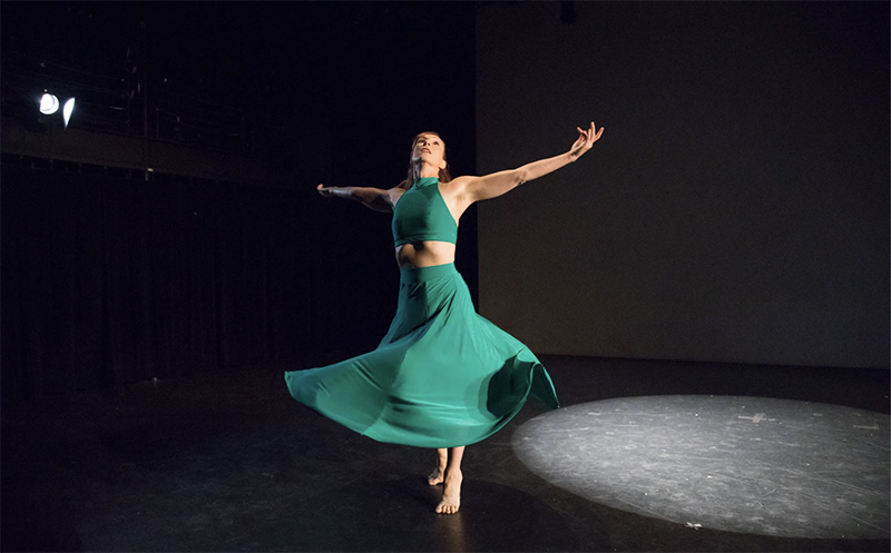 Woman dancing with arms outstretched.