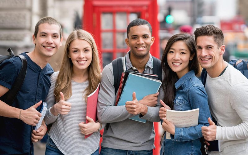 5 students side by side smiling with their thumbs up