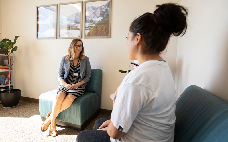 Female counselor talking with woman in therapy session.