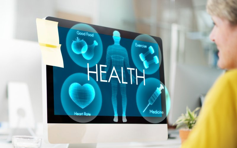 A women looking a a computer screen with health icons.