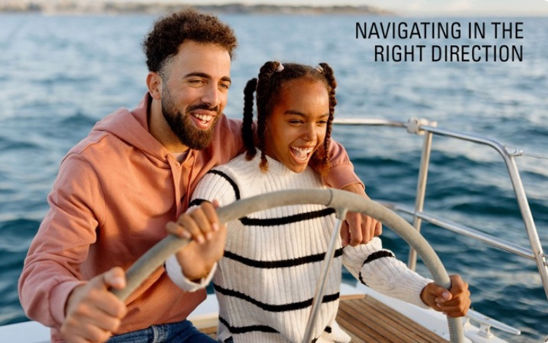 A father and daughter steering the wheel of a boat