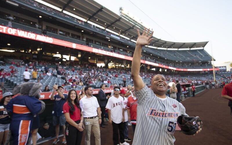 man in a baseball jersey waving to a crowd at a baseball stadium