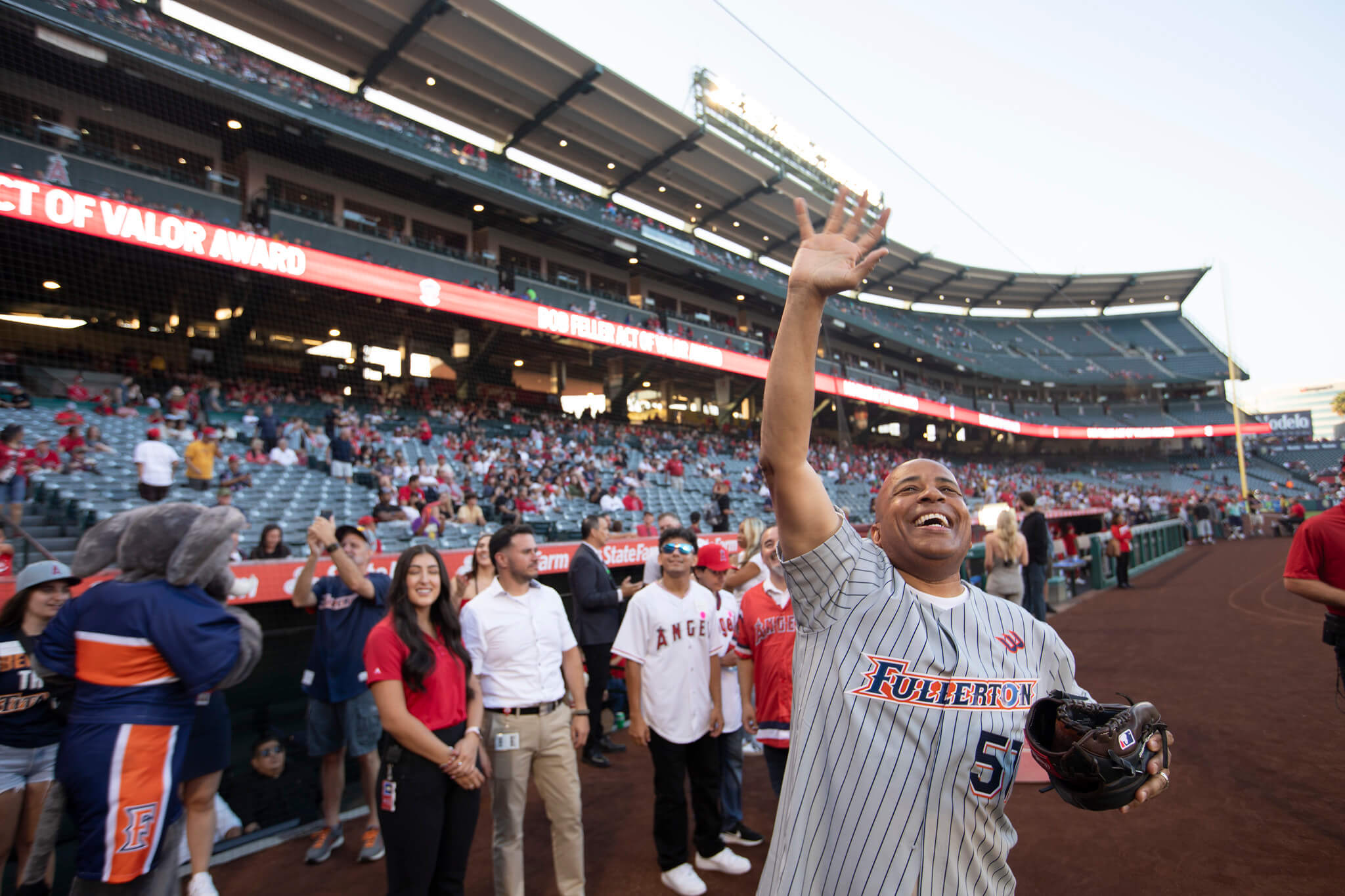 man in a baseball jersey waving to a crowd at a baseball stadium