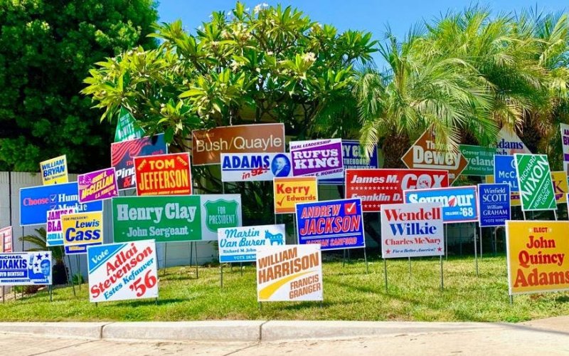 A residential front yard with 59 election style signs with the names of past individuals who has unsuccessful runs to be President of the United State of America.