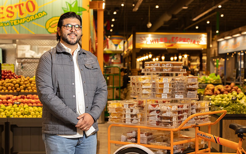 Man standing in a grocery store with a cart full of packaged goods.