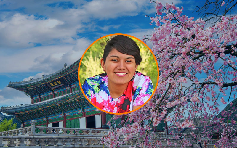 Circular image frame outlined in orange with a headshot of Juli Avila. Behind the frame is a background image of a temple in Seoul, South Korea.