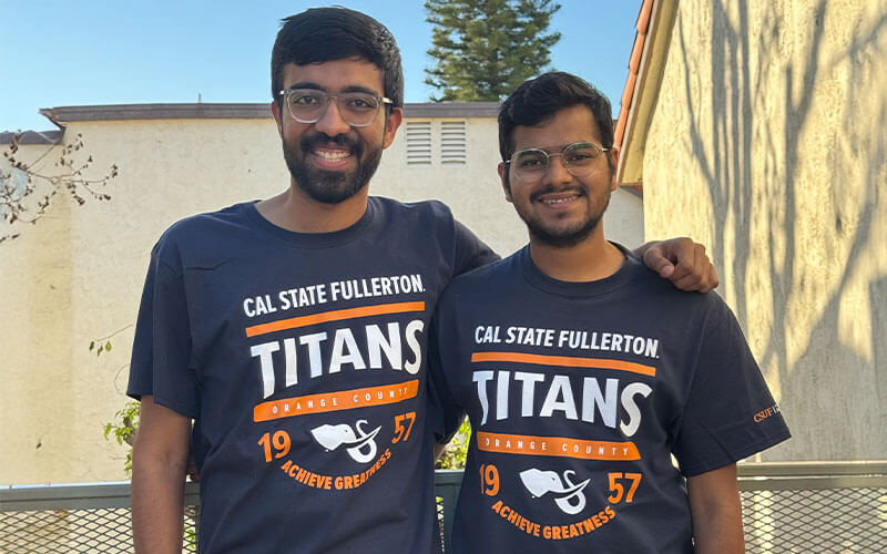 Two students wearing Cal State Fullerton t-shirts and smiling at the camera